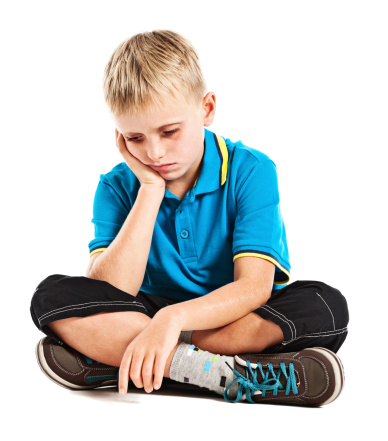 This 9 year old blond boy seems in a bad way. He might be depressed, sick or simply sad as he looks down, frowning. Isolated on white.