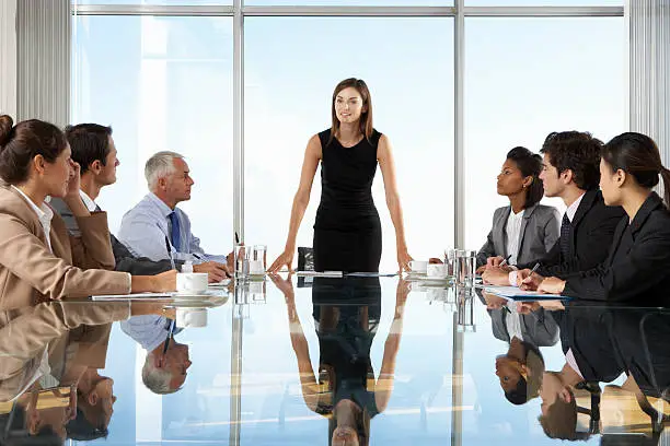 Group Of Business People Having Board Meeting Around Glass Table.