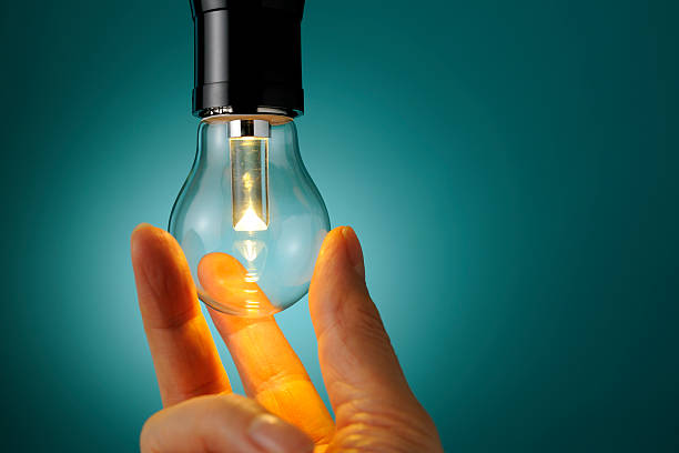Hands exchange old tungsten bulb to low power consumption LED