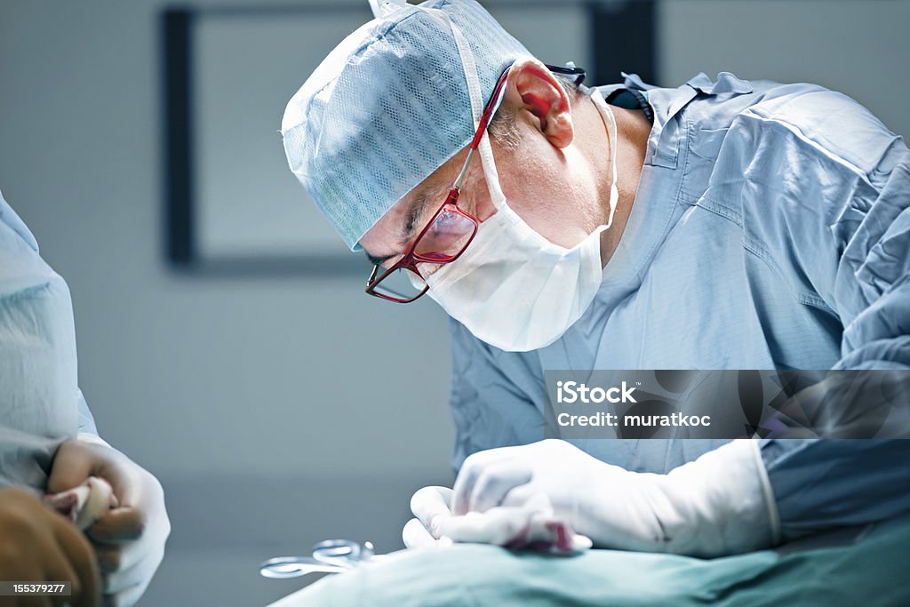 Surgeon performing surgery surgery in a operating room. Adults Only Stock Photo