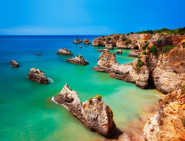 Saturated image of a colorful Algarve beach in Portugal Praia Do Vau in Algarve, Portugal with huge rocks on the beach. algarve stock pictures, royalty-free photos & images