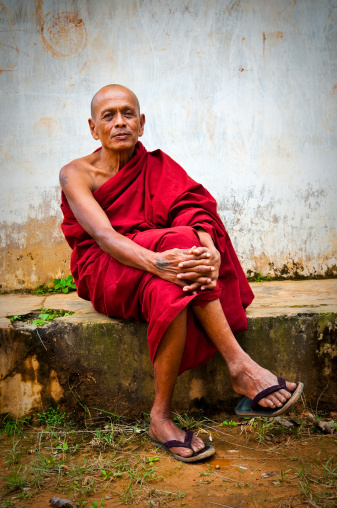 Portrait of a Burmese Buddhist monk sitting outside a building near Kalaw, Myanmar