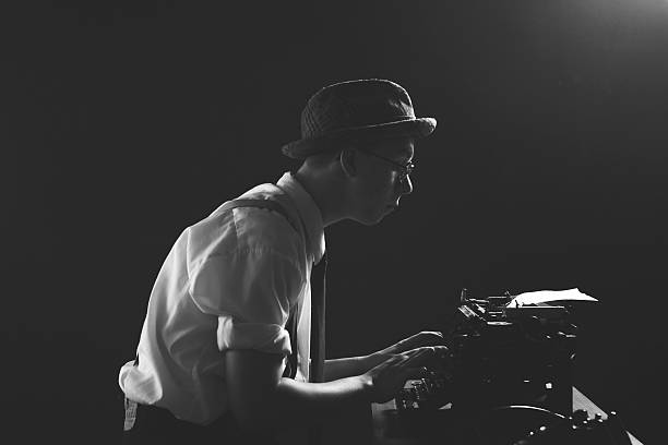 1920s Detective or Reporter Working Late Hours Studio Portrait of a young 1920s reporter or detective working long hours into the night. Complete with retro typewriter and telephone. Black and white with copy space. typewriter photos stock pictures, royalty-free photos & images