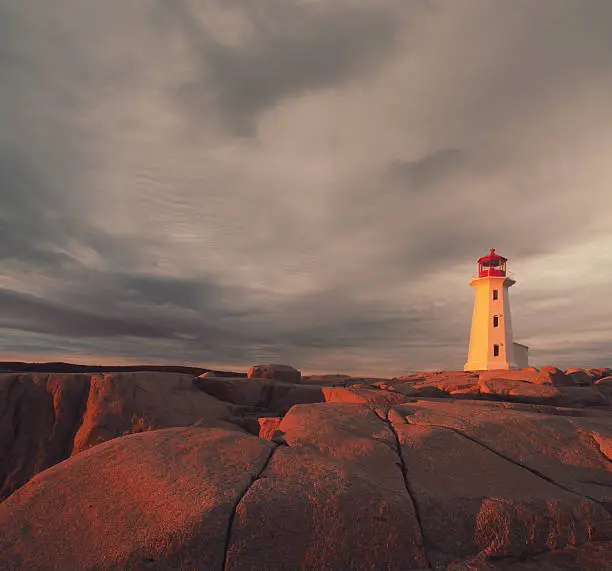 A thin sliver of clear sky lets the setting sun cast it's light on Peggy's Cove Lighthouse.