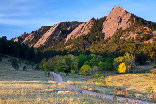 A path leads to the Flatirons in Boulder Colorado. Fall colors starting to show in the trees.