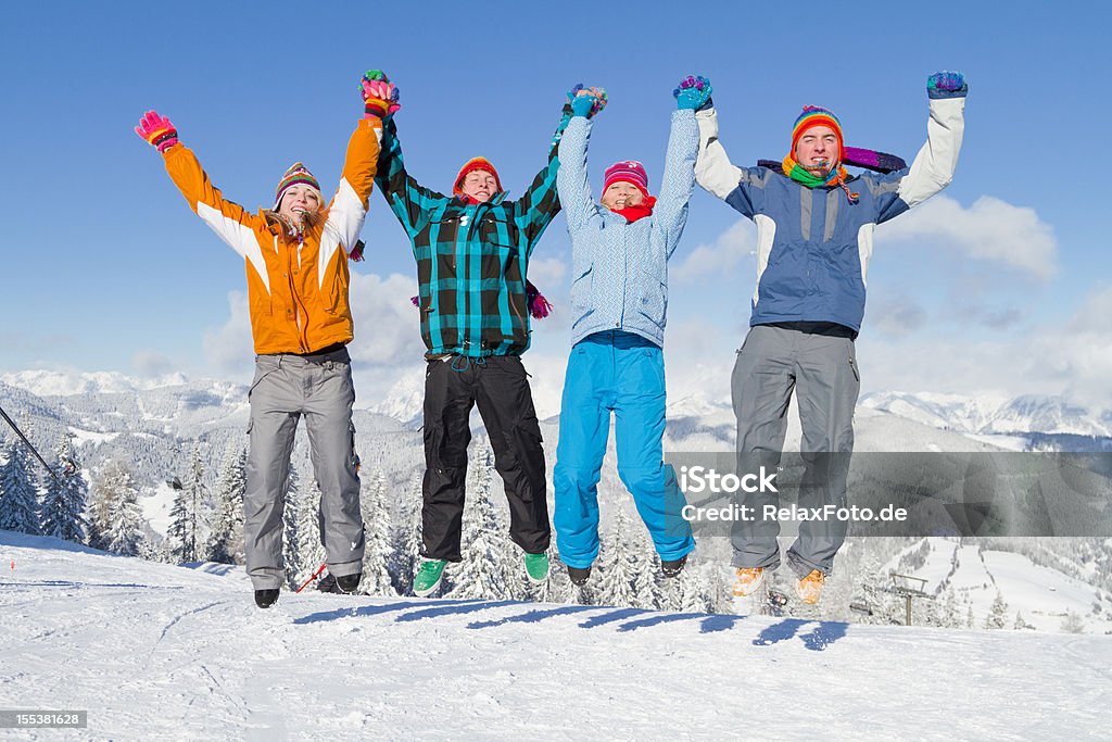 Quatre jeunes gens en vêtements d'hiver de sauter dans la neige - Photo de Activités après le ski libre de droits