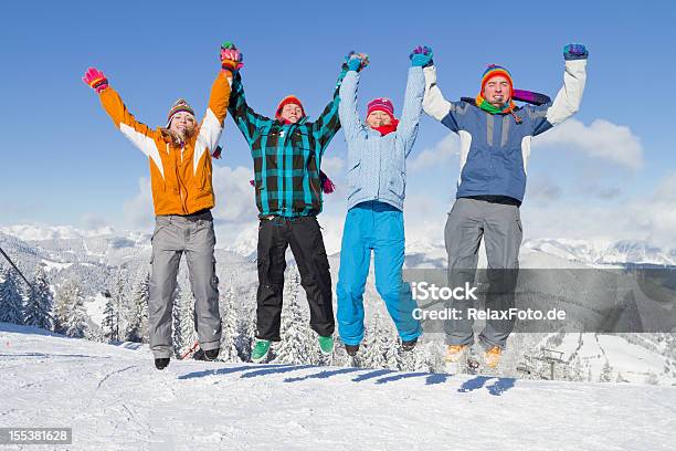 Photo libre de droit de Quatre Jeunes Gens En Vêtements Dhiver De Sauter Dans La Neige banque d'images et plus d'images libres de droit de Activités après le ski