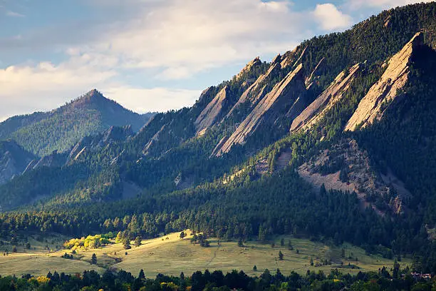A sunbeam lights up the Flatirons in Boulder Colorado in Fall.