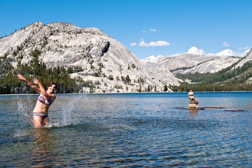 Happy woman and chorten (recently constructed by photographer for luck!) in Tenaya Lake, Yosemite, USA.