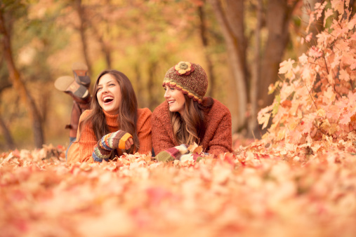 Two young women enjoy a conversation and leisure time in the autumn leaves.