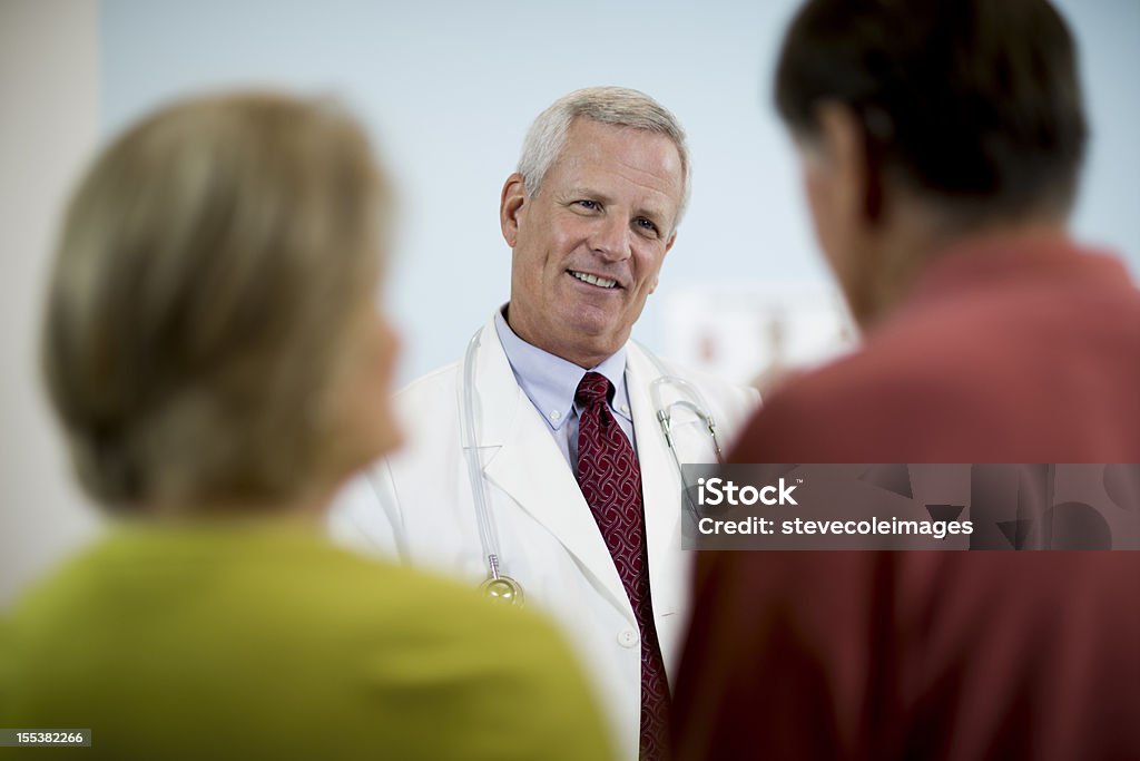 Médico explicando Medical resultados para parejas. - Foto de stock de 50-59 años libre de derechos