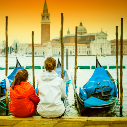 Tourists watching gondolas in Venice, with San Giorgio Maggiore church at the background - Venice, Italy