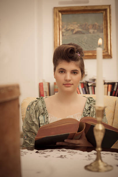 istock Victorian woman reading by candlelight 155382544