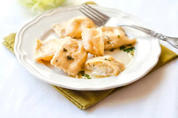 Cooked ravioli pasta filled with ricotta and mozzarella cheese with sauce of butter basil and parmesan cheese.