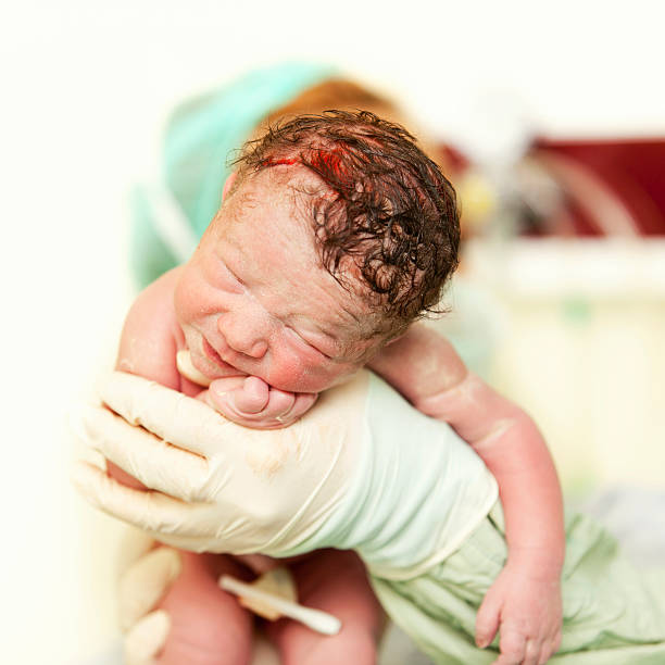 doctor holding a beautiful baby girl minutes after the birth stock photo