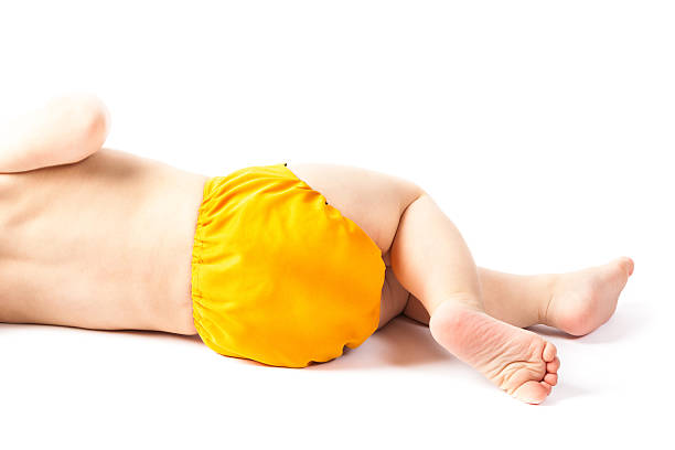 Baby lying sideways with yellow cloth diaper on white background stock photo