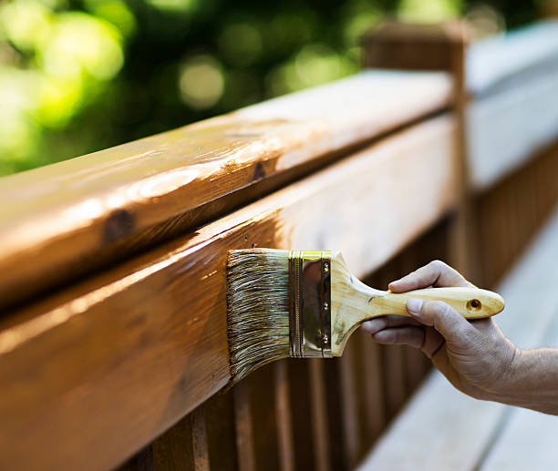 Male Carpenter Applying Varnish To Wooden Furniture. stock photo