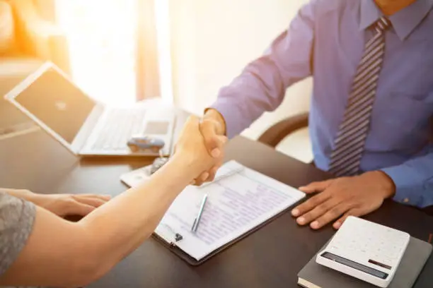 Photo of car dealer shook hands with buyer as sign of successful deal and a thank you after the car purchase contract was signed. concept of a handshake to express gratitude after a successful sale contract.