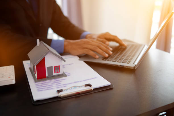istock real estate agent sits and checks customer information with laptop computer located on desk in office before passing information to finance company in order to lend them loan to buy real estate. 1553832880
