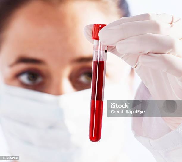 Photo libre de droit de Sérieux Femme Scientifique Examine Fiole De Liquide Rouge Sang Peut banque d'images et plus d'images libres de droit de Adulte