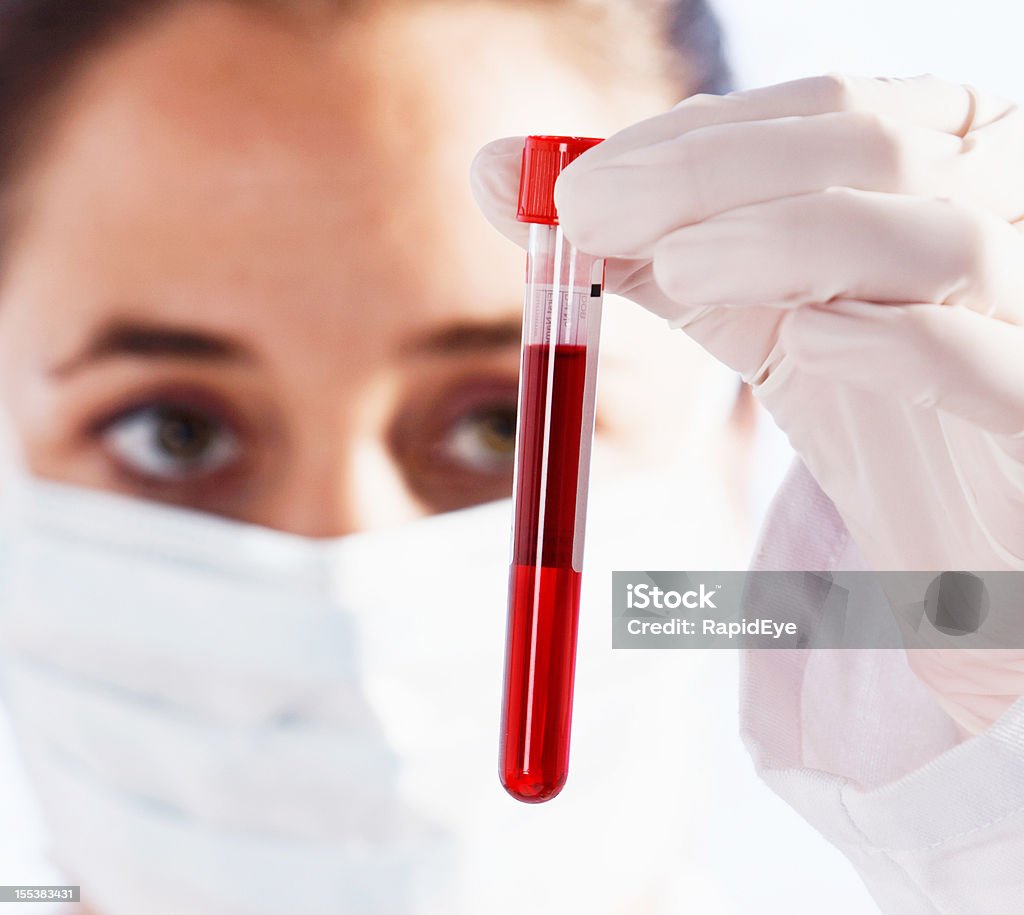 Grave femmina Scienziato esaminando flacone di liquido rosso sangue eventualmente - Foto stock royalty-free di Adulto