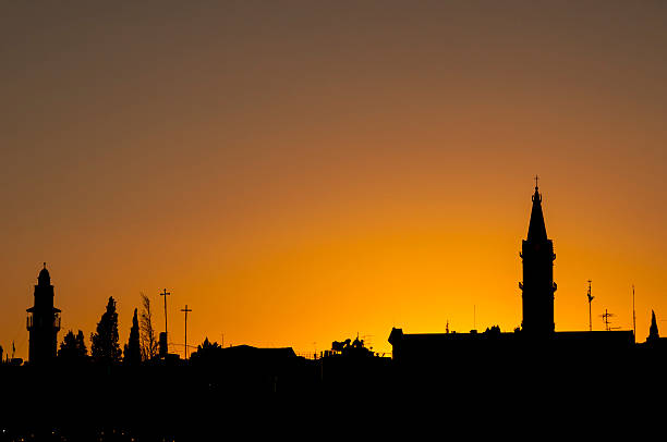 Sunset over the old city in Jerusalem. The minaret of a mosque is on the left; on the right is a church tower.