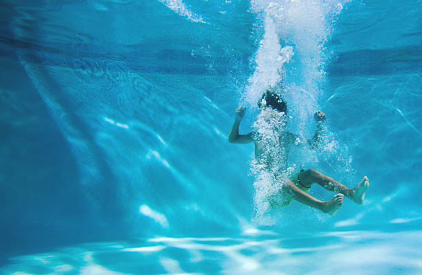 boy diving into a swimming pool boy diving into a swimming pool, bubbles covering his face just do it stock pictures, royalty-free photos & images
