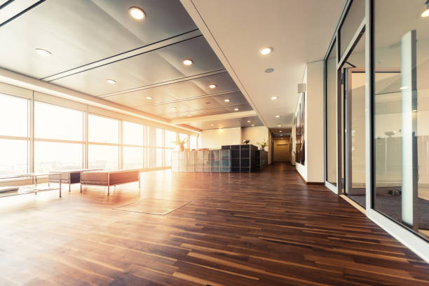 Office reception with wood floors and window wall A large open plan office space with a wooden floor and decorative ceiling.  Full height windows run along the full length of the office space. ceiling stock pictures, royalty-free photos & images