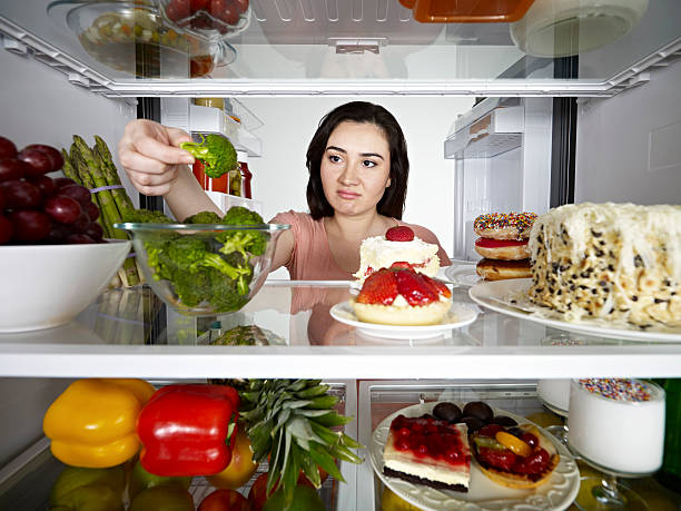 istock Young woman taking broccoli out of a fridge 155384130