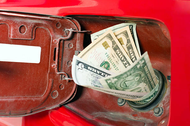 Money in the chute of a gas representing high gas prices This is the place where all your money has been going lately. fuel prices photos stock pictures, royalty-free photos & images