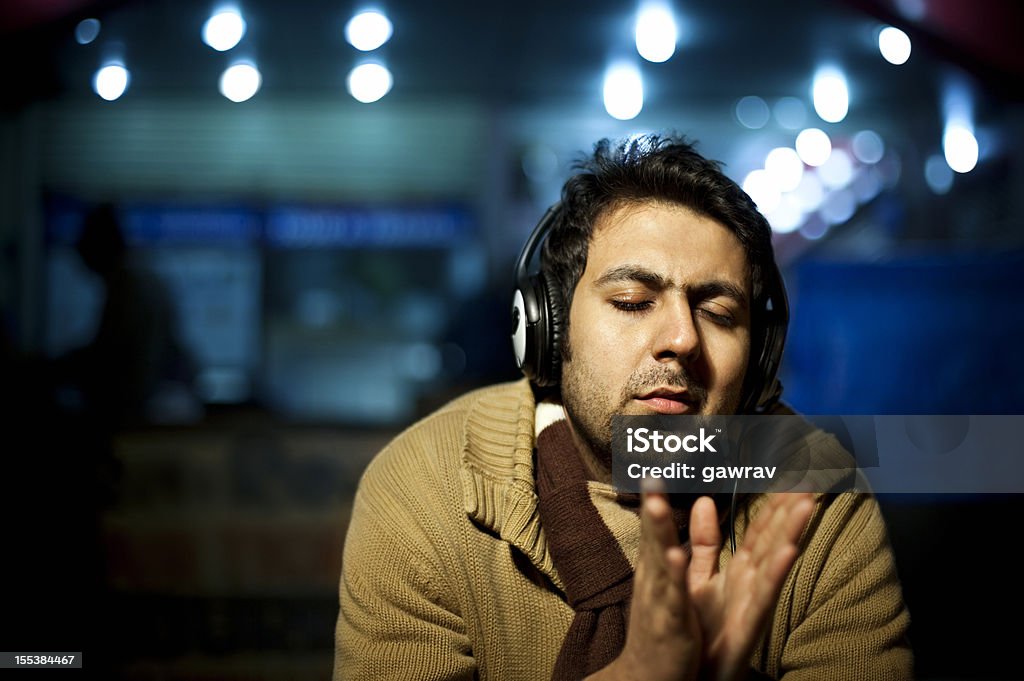 Giovane uomo ascoltando musica all'aperto di notte - Foto stock royalty-free di 25-29 anni