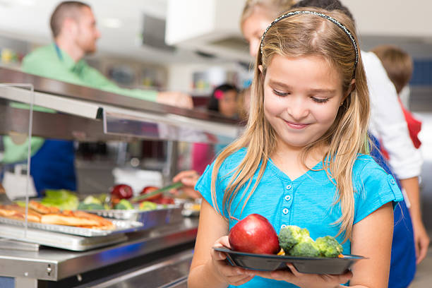 Happy little girl making healthy choices in school cafeteria Happy little girl making healthy choices in school cafeteria.  cafeteria school lunch education school stock pictures, royalty-free photos & images