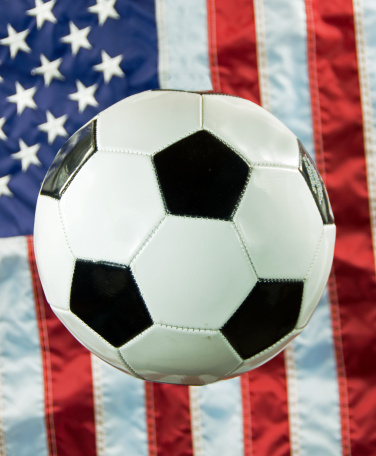 A soccer ball with an American flag in the background.