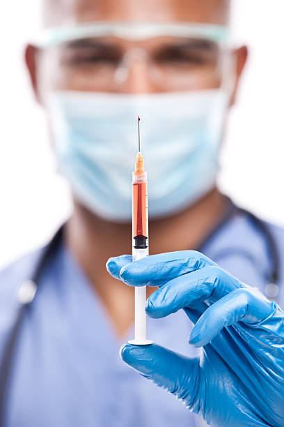 Black Doctor with Needle Closeup photo of a surgical needle in the hand of an african american male doctor. red medical scrubs stock pictures, royalty-free photos & images