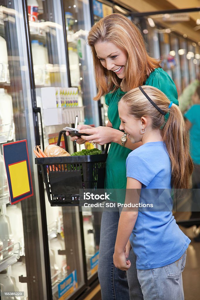 Mãe e filha fazendo compras no supermercado juntos - Foto de stock de Filha royalty-free