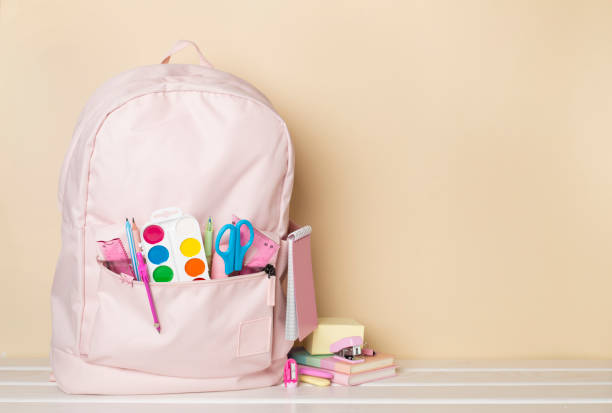 istock Pink school backpack with stationery on wooden table 1553852309