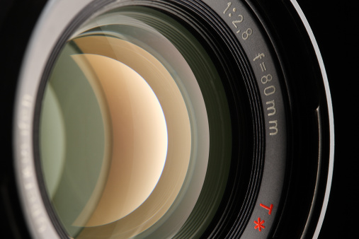 Close up of a new camera lens on blurred grey background. Action. Details of professional photographer equipment