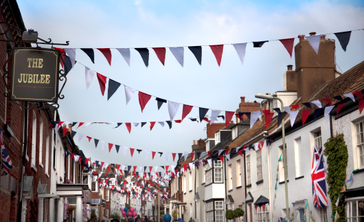 An English street decorated with flags and bunting to celebrate the Queen's Jubilee in 2012.  The sign has been created by the photographer and the words \