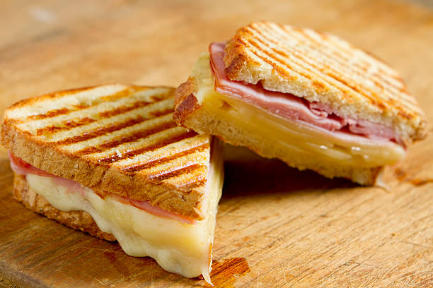 Sliced panini sandwich on wood surface Hot off the grill panini sandwiches made with crusty, hand sliced bread, black forest ham and swiss cheese. ham and cheese sandwich stock pictures, royalty-free photos & images