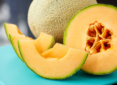 Sliced cantaloupe on blue cutting board.  Exported 16 bit depth, color corrected and retouched for maximum image quality.