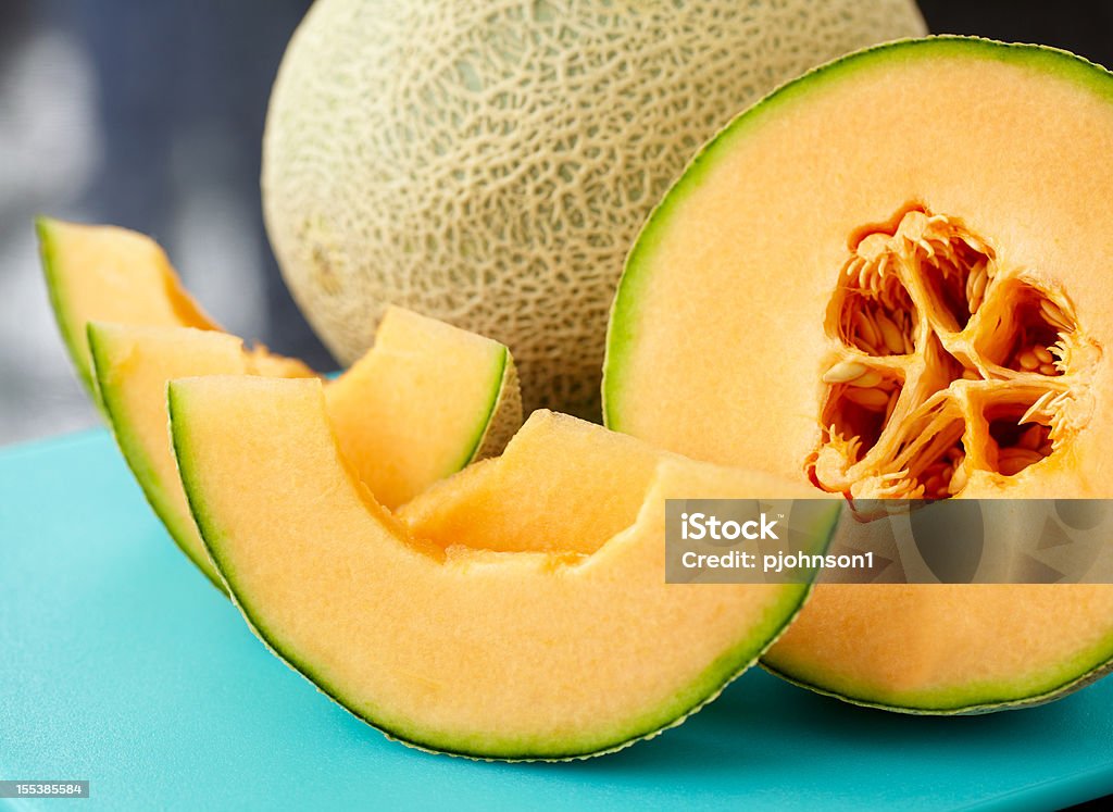 A close up of a sliced cantaloupe on a blue table Sliced cantaloupe on blue cutting board.  Exported 16 bit depth, color corrected and retouched for maximum image quality. Cantaloupe Stock Photo