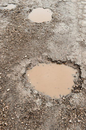 A pothole in the middle of the street awaits its next victimThe spring freeze and thaw cycle cracks the roadbed and leads to the creation of potholes.