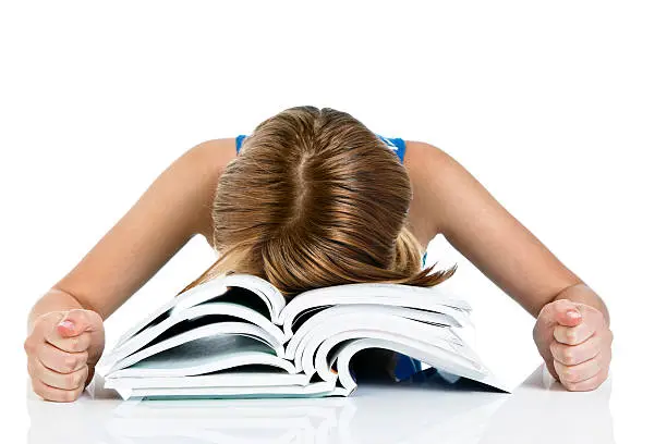 This young female student has obviously had quite enough of studying as she falls face forward into a pile of books, fists clenched in frustration.