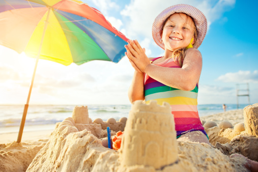 Happy little girl building a sandcastle. 