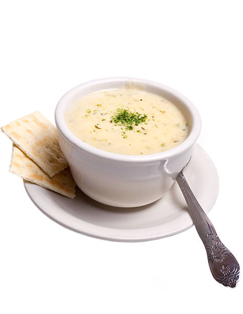 Hot and Creamy Traditional New England style Clam Chowder soup in a white bowl and spoon Isolated on White