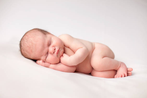 Color Image of Newborn Baby Sleeping Peacefully Color image of a newborn baby sleeping peacefully, on white background. lying on side stock pictures, royalty-free photos & images