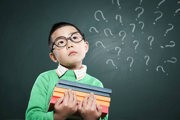 istock one boy stands in front of the blackboard 155386991