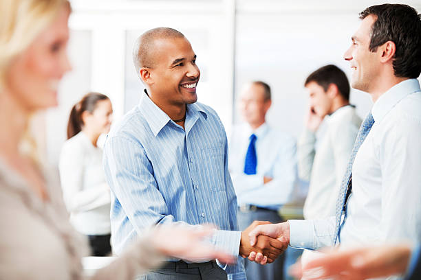 deux hommes d'affaires se serrant la main dans un cadre - business meeting smiling ethnic multi ethnic group photos et images de collection