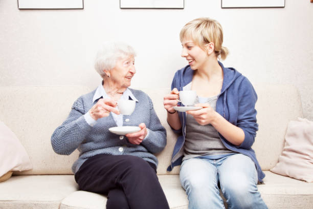 istock senior woman and caregiver talking drinking coffee 155387243