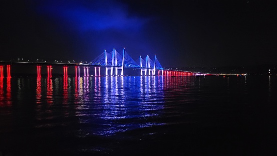 July 4, 2023- The former Tappan Zee Bridge in New York is lit up in red, white and blue, for Independence Day- lights are reflected in the Hudson River